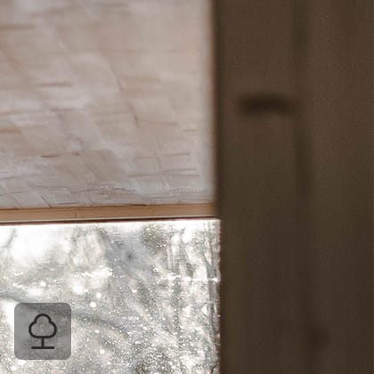 Ujęcie wnętrza pokoju wykończonego jasnym drewnem, pokazujące narożnik oraz duże okno z widokiem na ośnieżony krajobraz.