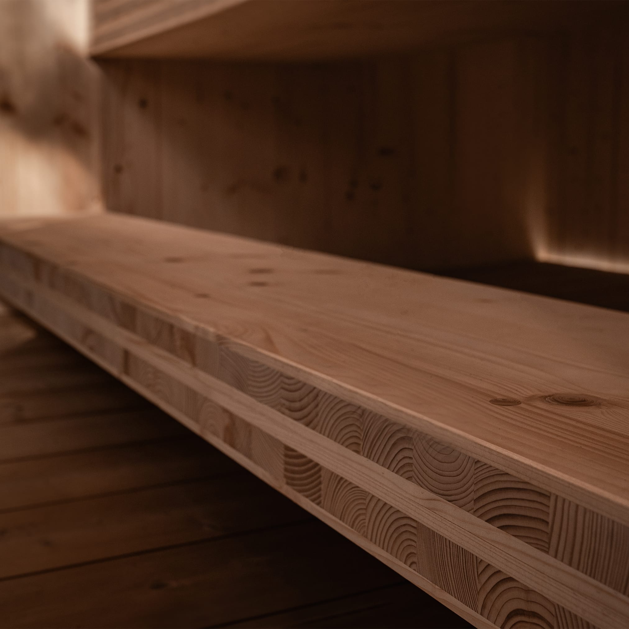 An angular close-up of a solid light wood beam in a sauna, showing its layered construction of glued beams and visible grain.