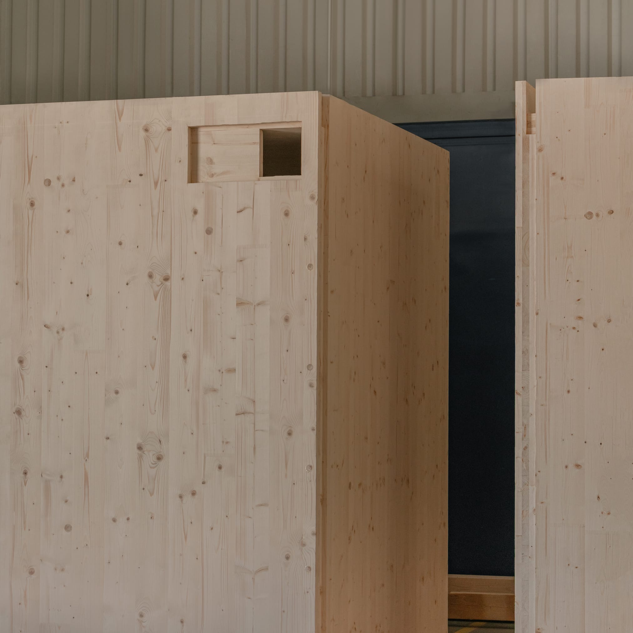 Zbliżenie na masywne, prefabrykowane moduły z jasnego drewna konstrukcyjnego (CLT) stojące w hali produkcyjnej.