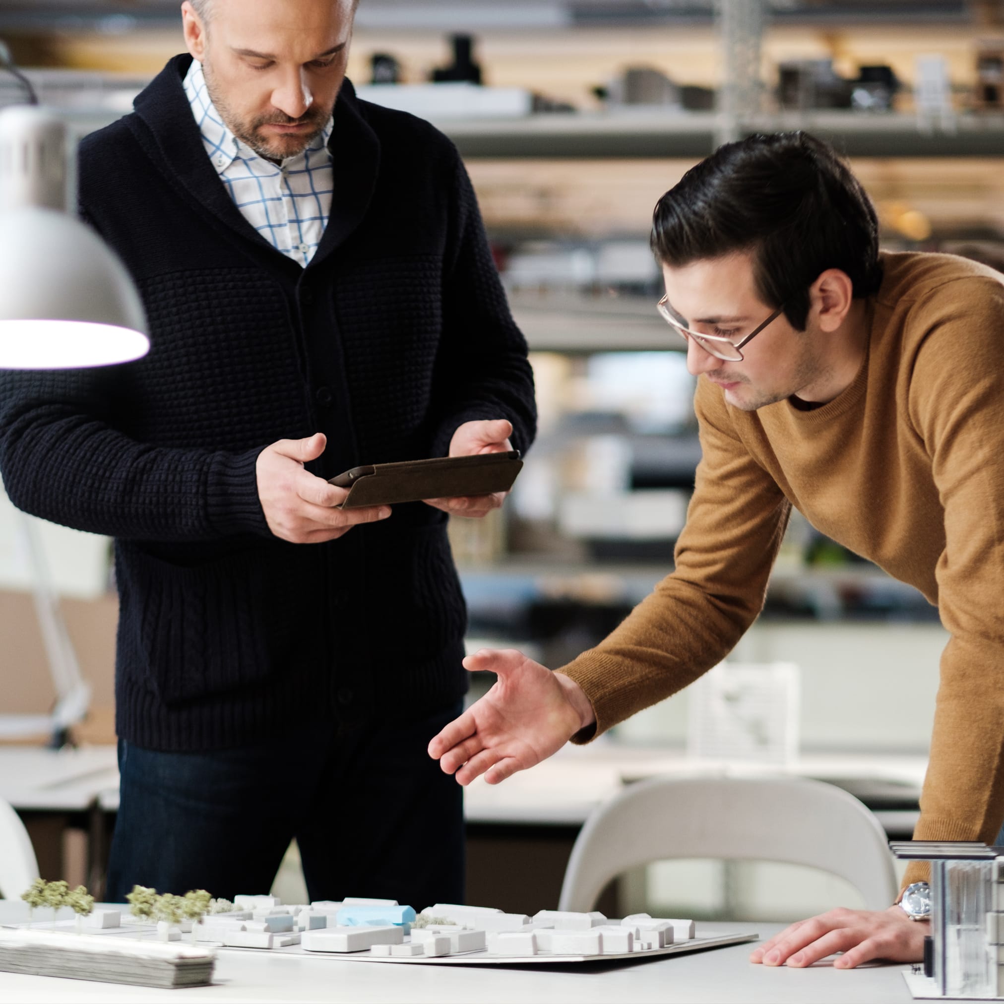 A person writing on a piece of paper with a laptop in the background.