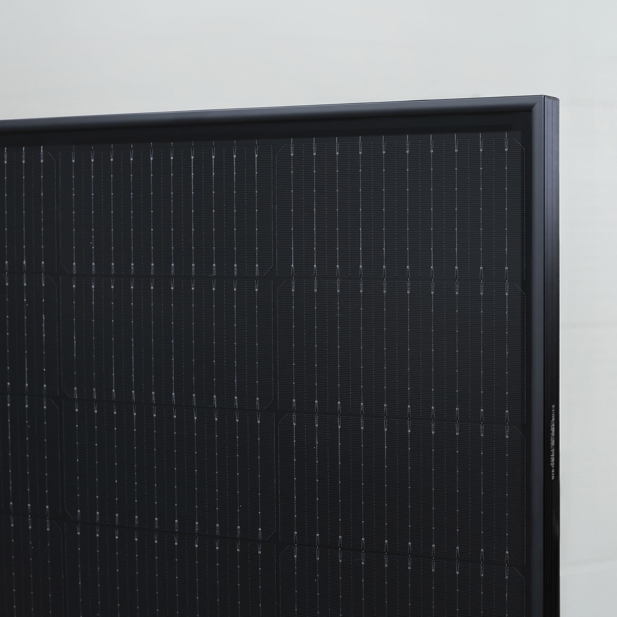A close-up of a pitched roof covered with dark, integrated photovoltaic panels that form a smooth, uniform surface.