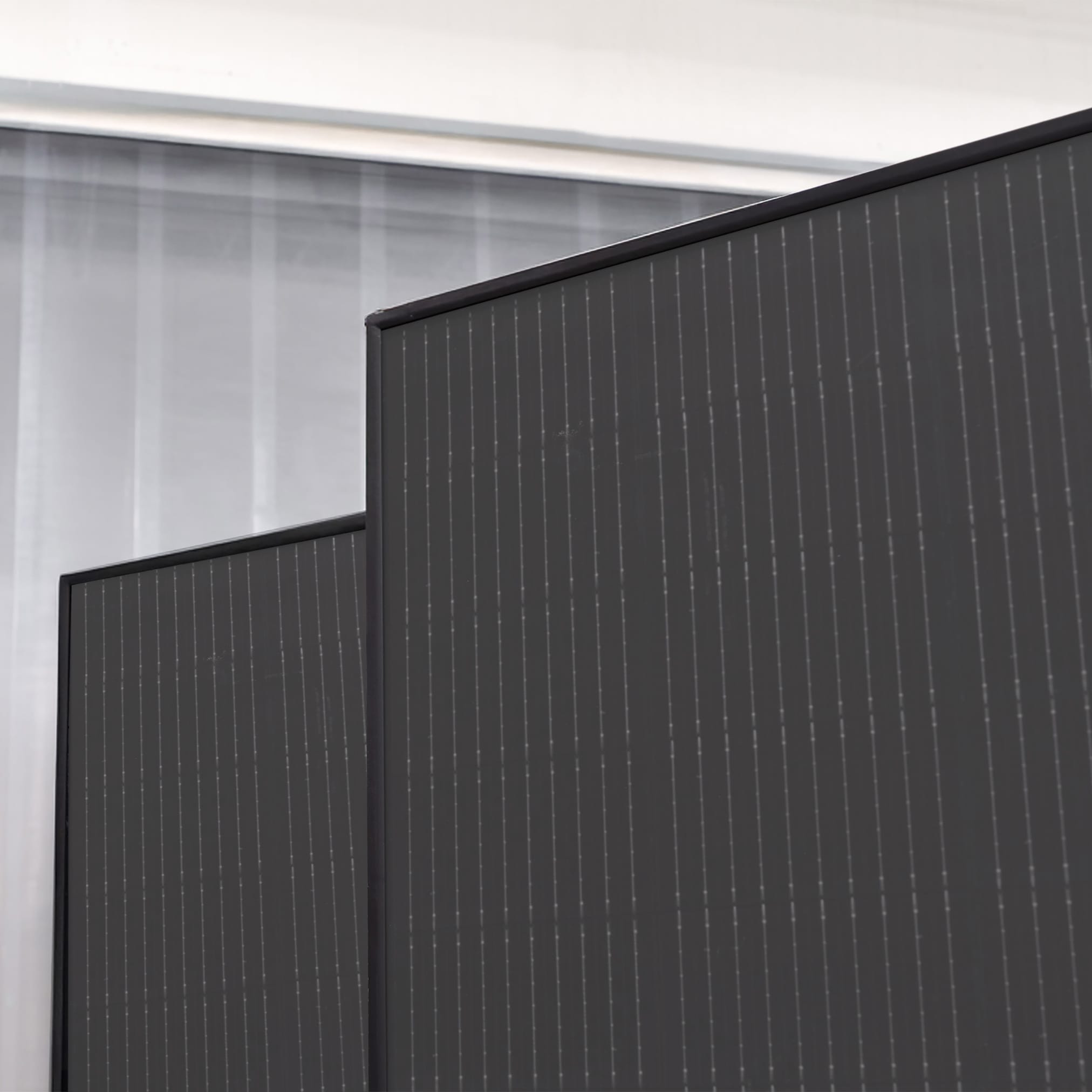 A close-up of a pitched roof covered with dark, integrated photovoltaic panels that form a smooth, uniform surface.