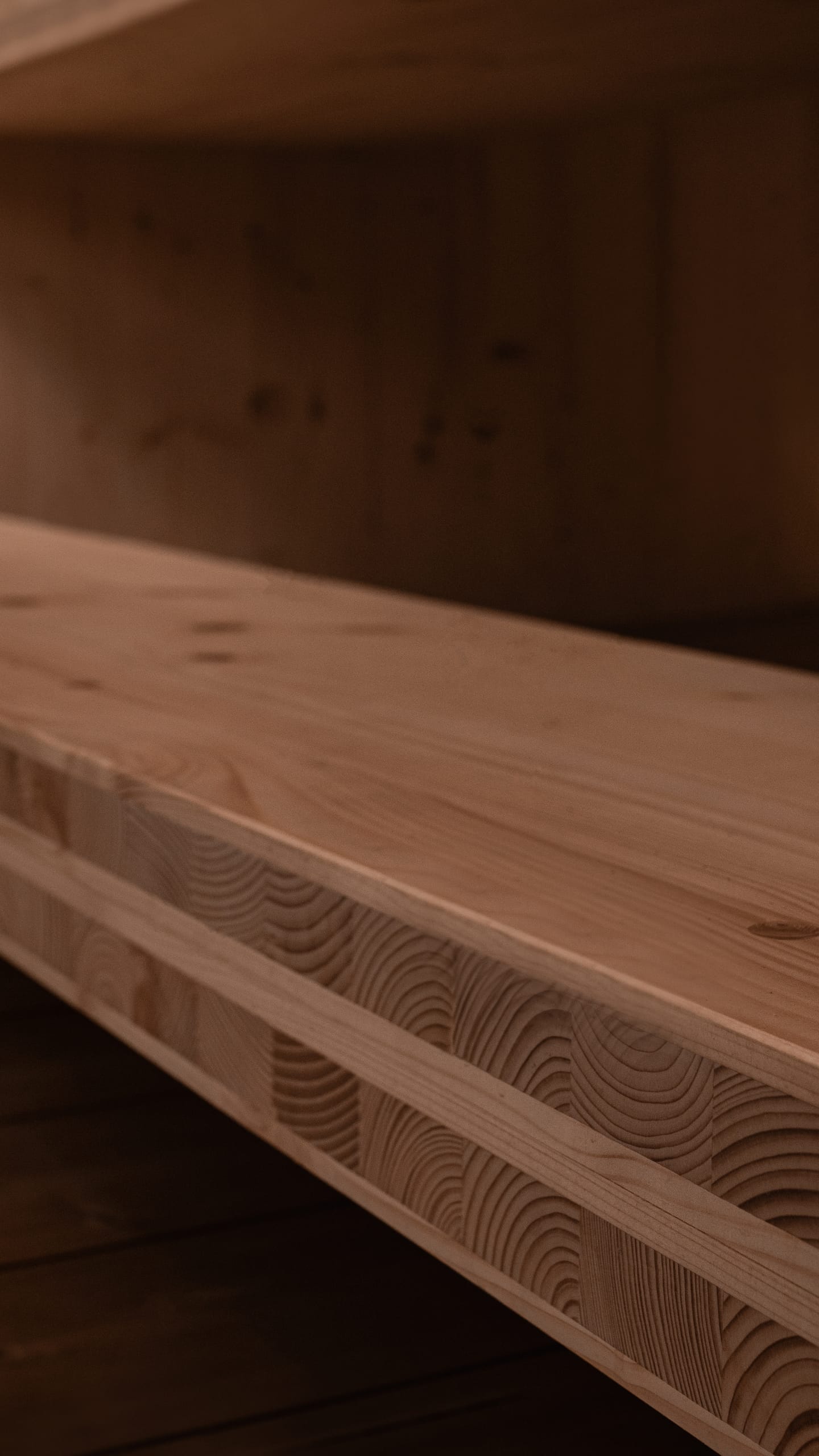 An angular close-up of a solid light wood beam in a sauna, showing its layered construction of glued beams and visible grain.