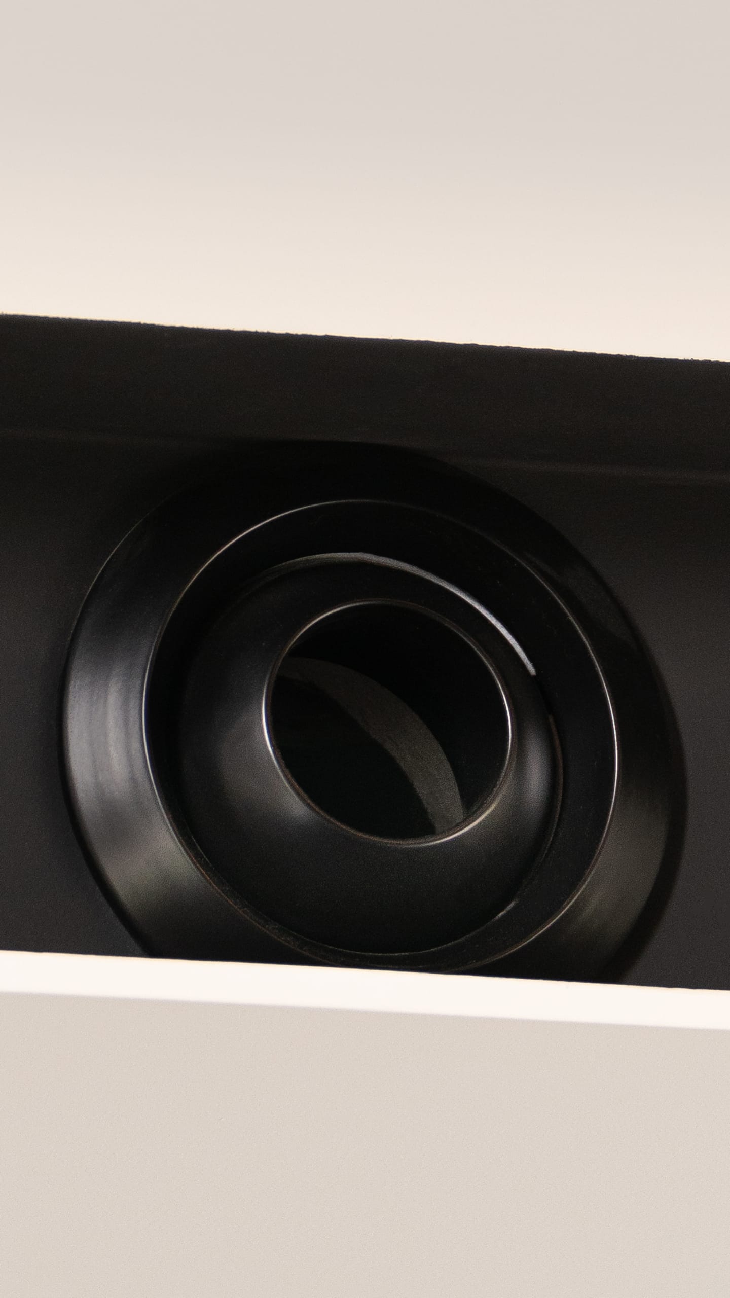 Corner of a bright room with a black ventilation grille on a white wall.