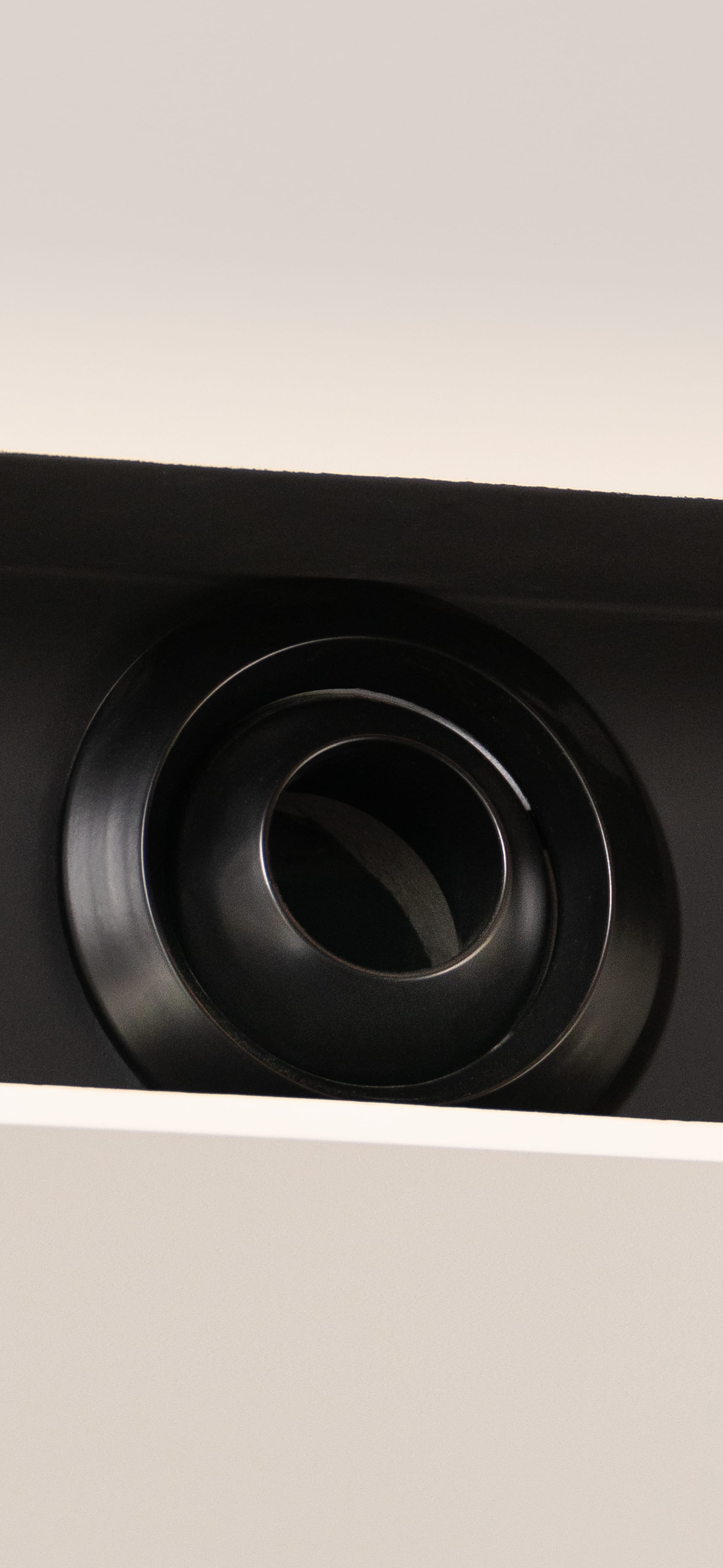 Corner of a bright room with a black ventilation grille on a white wall.