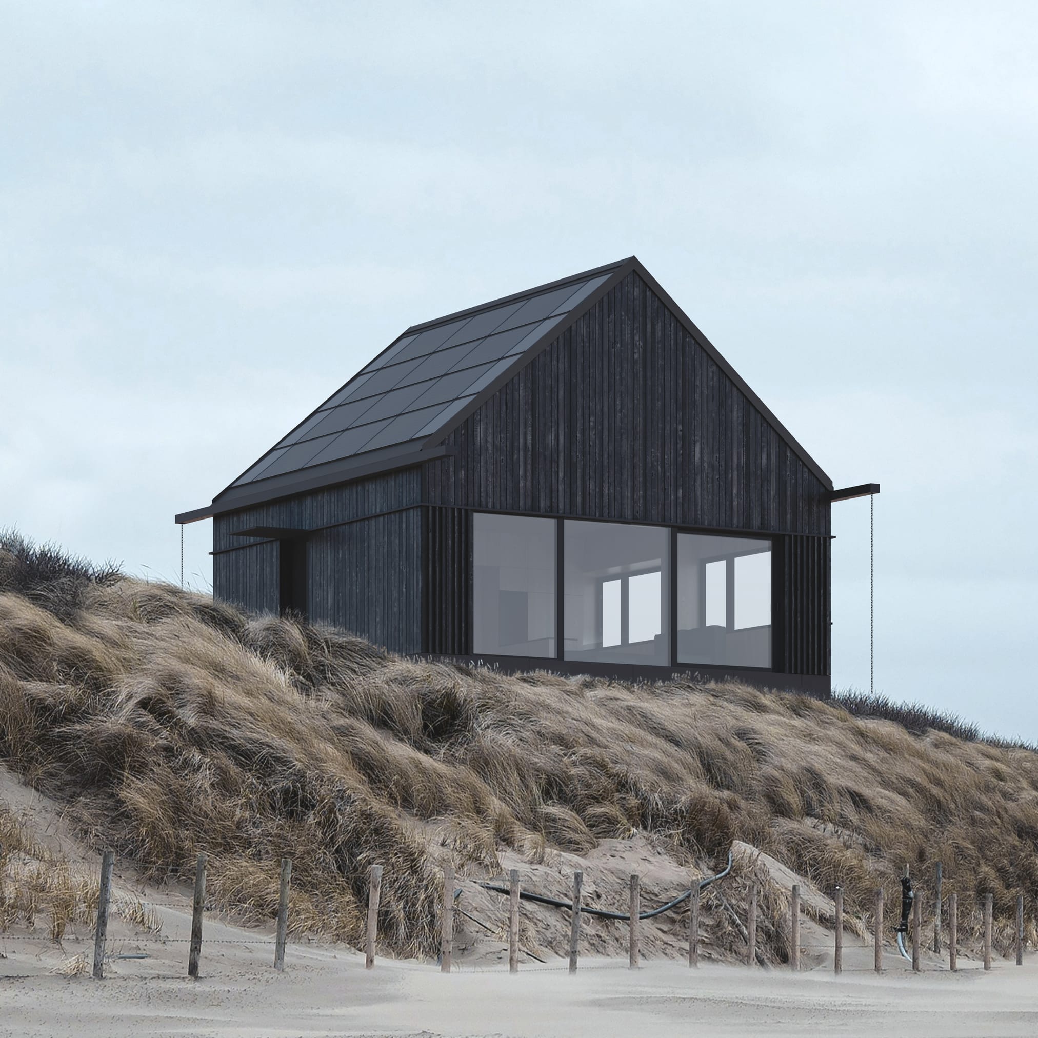 Dwa budynki- dom i sauna z czarnego drewna na wzgórzu porośniętym suchą trawą. Jeden ma spadzisty dach, a drugi ma kształt sześcianu.