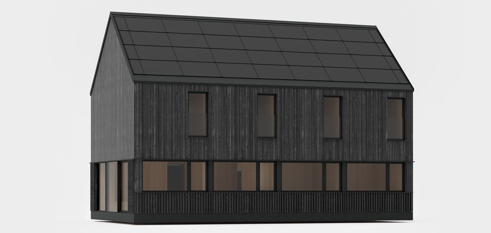 A dark, modern house with a roof entirely covered with photovoltaic panels, standing on a meadow at the foot of forested mountains.