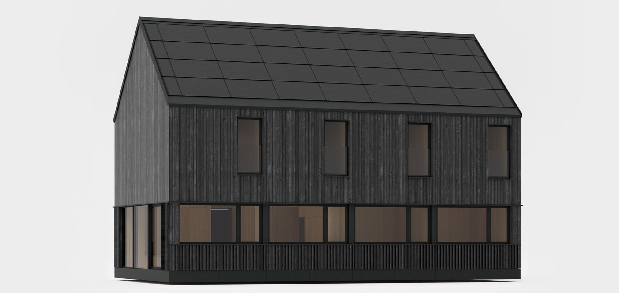 A dark, modern house with a roof entirely covered with photovoltaic panels, standing on a meadow at the foot of forested mountains.