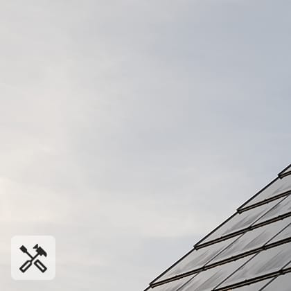 A close-up of a pitched roof covered with dark, integrated photovoltaic panels that form a smooth, uniform surface.