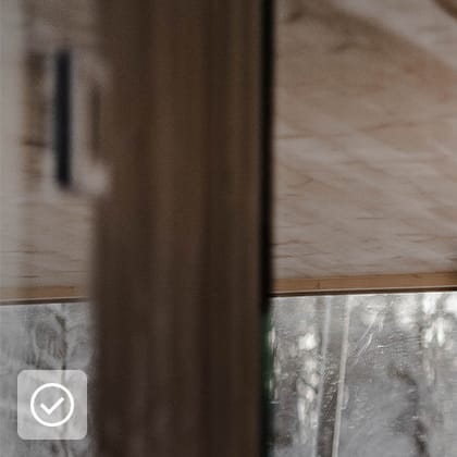 A shot of the interior of a room finished in light wood, showing a corner and a large window with a view of a snowy landscape.