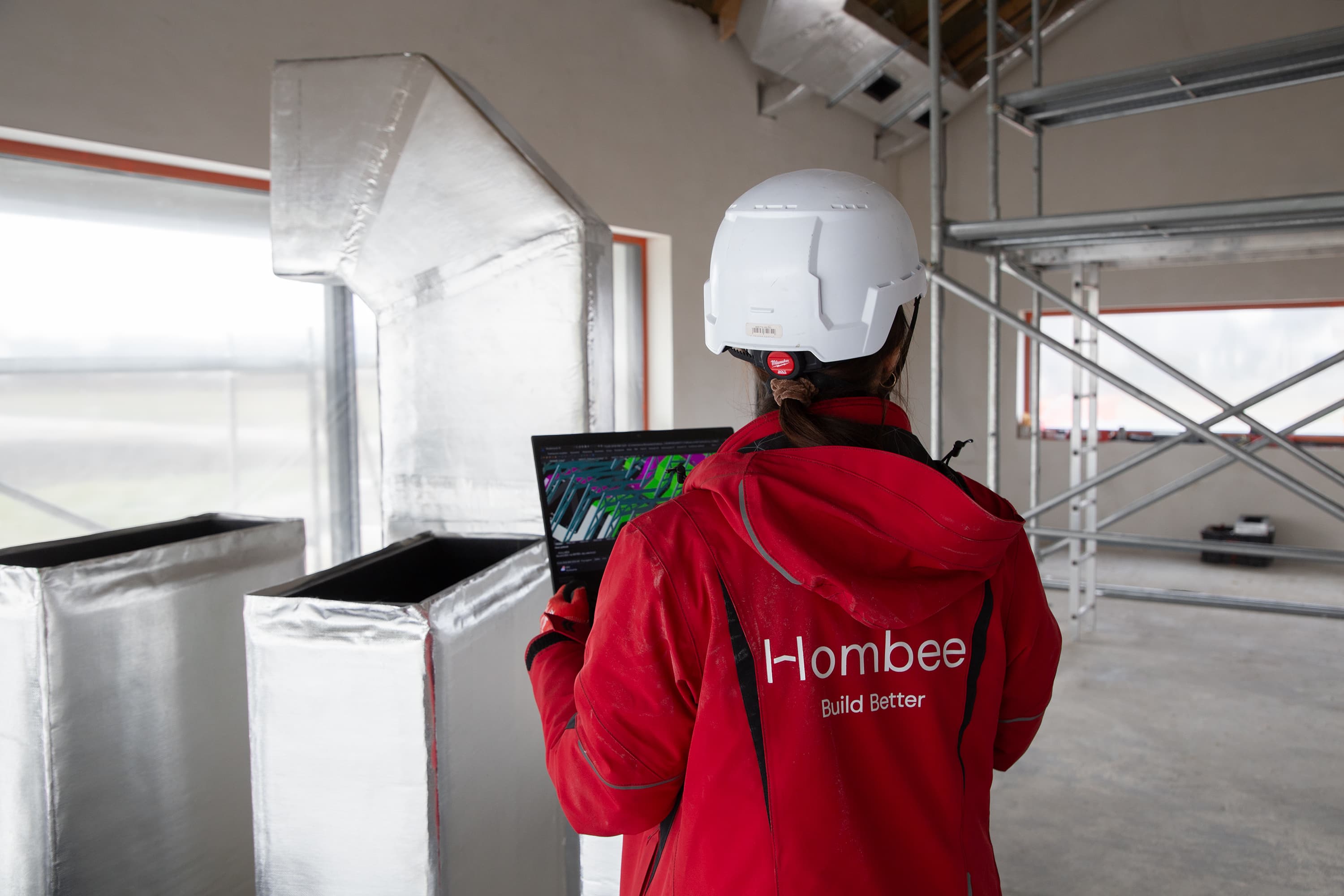 Specjalistka Hombee sprawdzająca model instalacji budynku na laptopie na placu budowy.