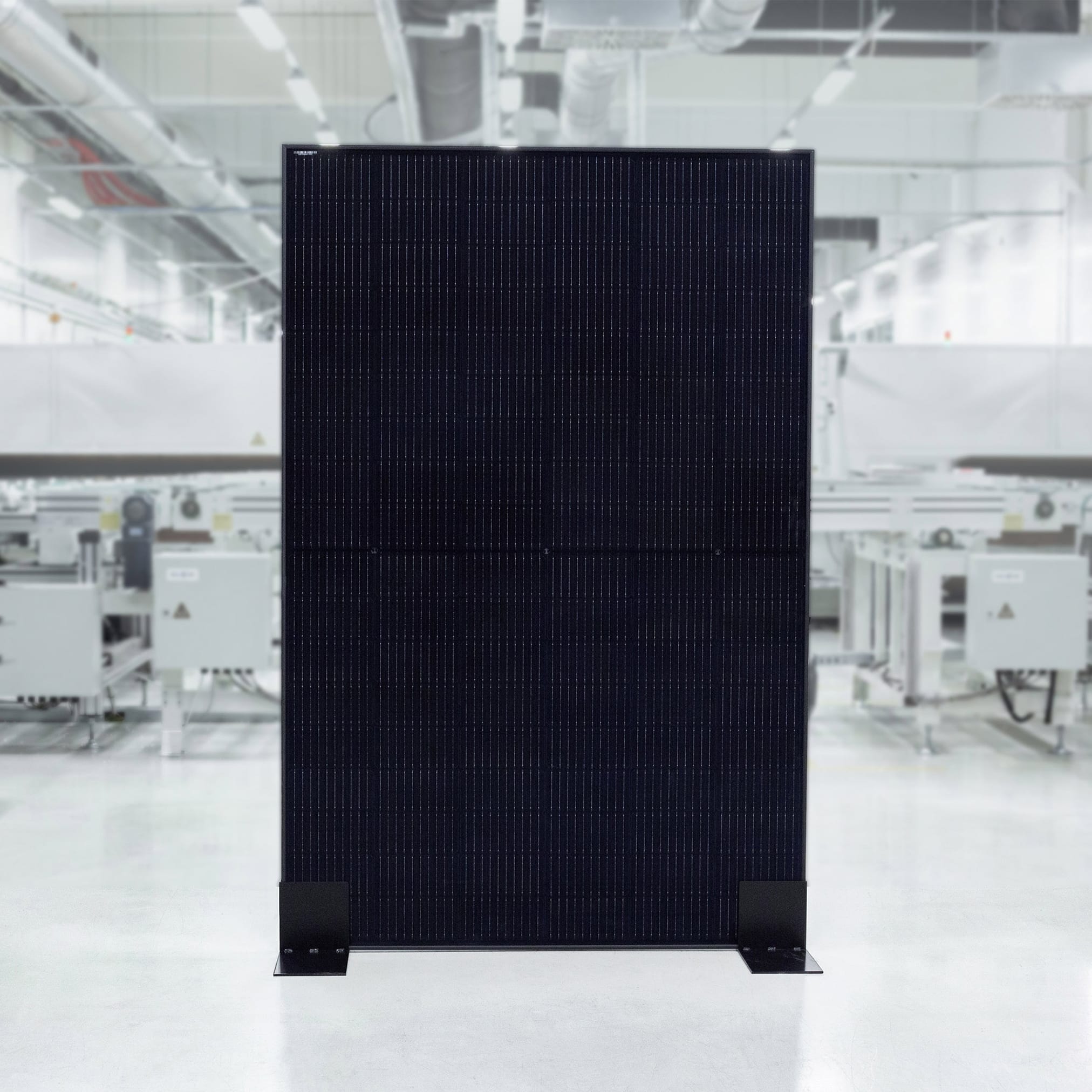 A black photovoltaic panel standing in a bright, sterile, modern production hall.