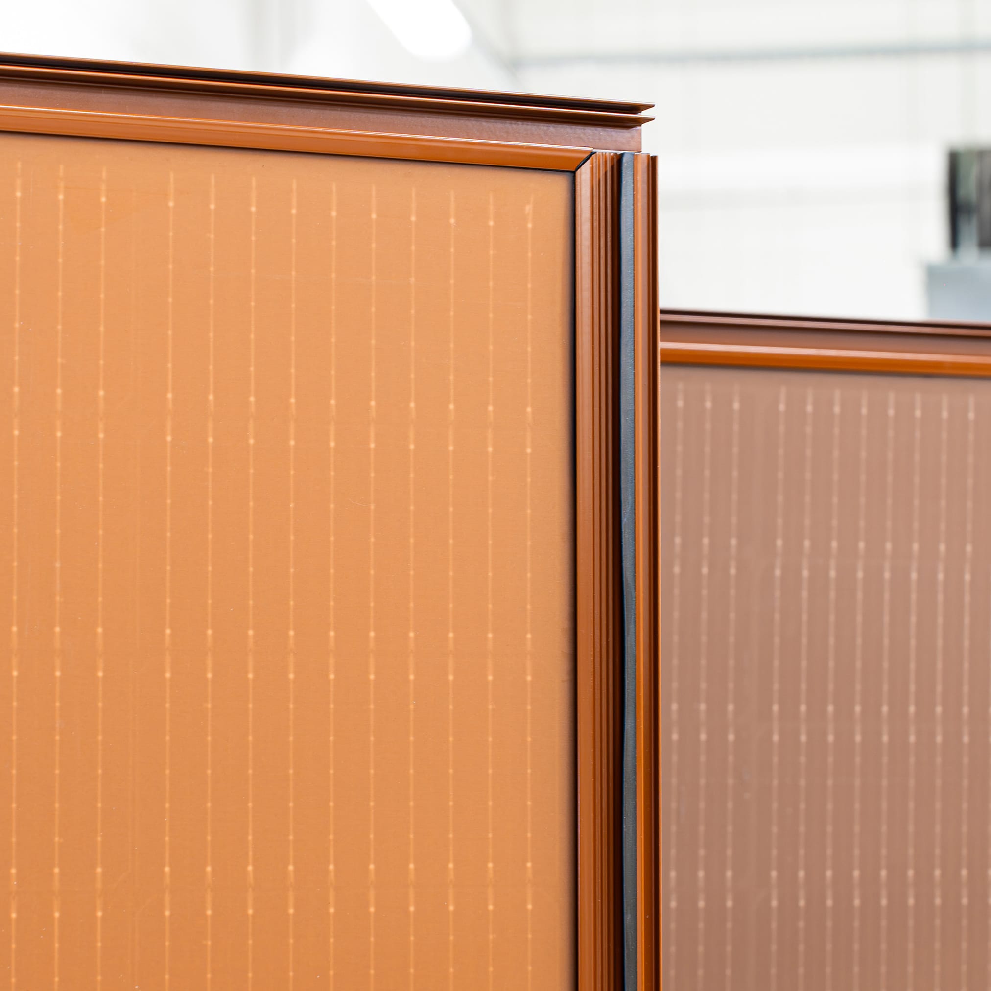 Zbliżenie na spadzisty dach pokryty ciemnymi, zintegrowanymi panelami fotowoltaicznymi, które tworzą gładką, jednolitą powierzchnię.